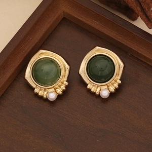 Vintage gold earrings with dark green beads and white pearls on wooden background