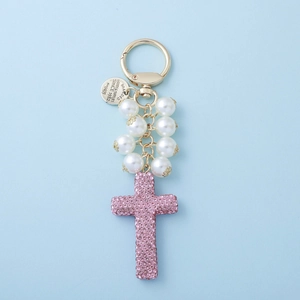 Beaded bow cross keychain with pink rhinestones and pearls on light blue background