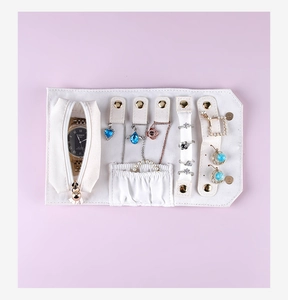 Detailed view of the white portable jewelry roll organizer with rings and watches inside