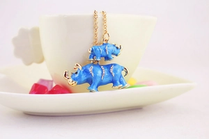 Detail showing two blue enamel rhinoceros pendants with crystal accents on a gold chain