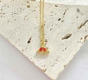 Macro shot of watermelon pendant necklace with red crystals on beige stone background