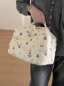 Close-up of quilted beige makeup bag featuring circus animal prints and soft ribbon bow