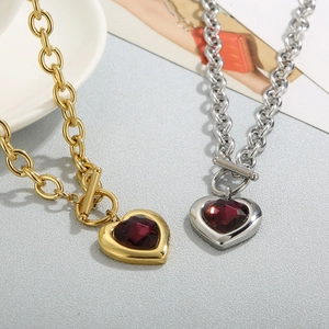 Close-up of gold and silver heart pendant necklaces with red crystal and OT toggle clasp