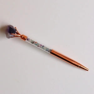Macro detail of rose gold metal pen featuring colorful natural crystal stone filling