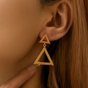 Close-up of matte 18K gold-plated double triangle earrings on a model's ear