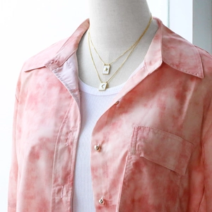 Detail of double-layered gold necklace with square star and moon pendants on a model