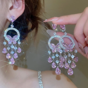 Macro detail of pink zircon butterfly tassel earrings featuring sparkling teardrop crystals