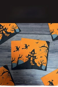 Flat lay of Halloween paper napkins with witch castle and pumpkin prints on dark wood