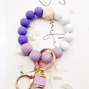 Detail of silicone bead keychain with purple leopard print, wooden bead and tassel charm