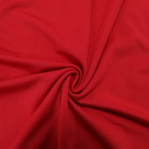 Detailed macro view showing the texture and drapery of red gathered knit dress fabric