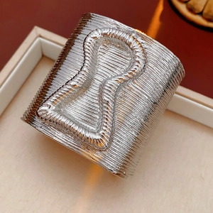 Macro shot of silver wide cuff bracelet with textured linear patterns in a jewelry box
