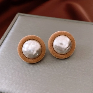 Macro shot of vintage round earrings with brown velvet borders and faux pearls