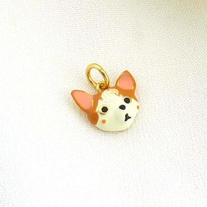 Macro shot of an orange and white enamel cat charm with a gold-plated metal ring