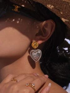 Close-up of gold and silver heart earrings and a diamond-studded open ring for women