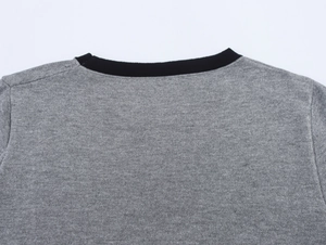 Gros plan détaillé du col rond côtelé noir sur un pull en maille gris contrasté
