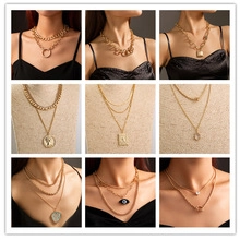 Collection of layered gold necklaces with star, coin, and evil eye charm pendants