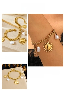 Detail of vintage gold sun star pendants and baroque pearl charms on a chunky chain bracelet