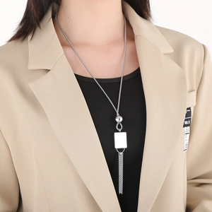 Detail view of a long silver tassel necklace with a rectangular geometric charm and fringe