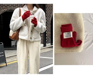 Detail view of red wool knitted long gloves featuring white profile garment brand labels