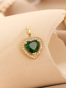 Detailed shot of golden heart pendant with emerald gemstone and zirconia halo