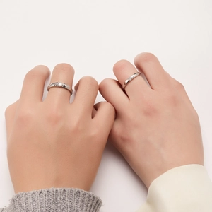 Minimalist silver couple rings with wave grooves and small diamonds on white background