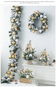 Close-up of white flocked Christmas wreath and trees with elegant gold ornaments