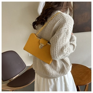 Detail view of yellow woven shoulder bag with golden chain strap and metallic lock