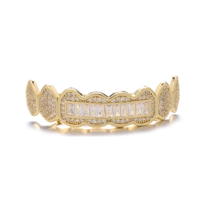 Macro detail of gold plated hip hop grillz with sparkling crystals on white background