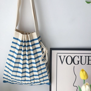 Close-up of pleated knit handbag featuring blue and white stripes in a stylish setting