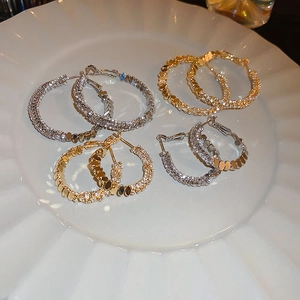 Lot de créoles en argent et or avec zircons de différentes tailles sur plateau blanc
