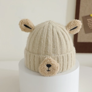 Detail of beige ribbed knit toddler hat featuring plush bear ears and stitched snout