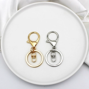 Detail view of gold and silver lobster clasp keyrings on a white ceramic plate