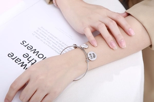 Detailopname van zilveren roestvrijstalen armband met hartvormige True Love bedel op pols
