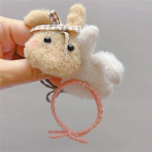 Detail of handmade beige wool felt bunny hair tie with plaid bow on pink elastic band