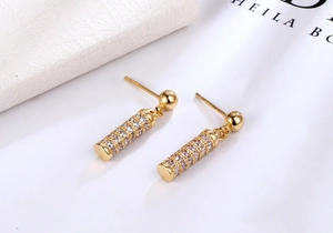 Macro detail of gold cylinder drop earrings with micro-paved sparkling cubic zirconia
