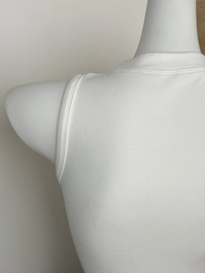 Nahaufnahme des weißen Stricktops ohne Ärmel mit Stehkragen und feiner Texturdetails