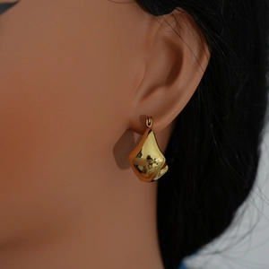 Modern chunky hollow oval golden earrings for women shown on a model side profile
