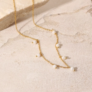 Elegant 18K gold stainless steel necklace with delicate white pearls on stone surface