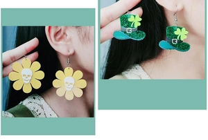 Close-up of Halloween acrylic earrings featuring a skull sunflower and a glitter clover hat