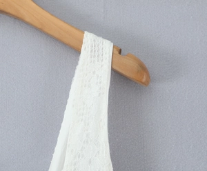 Gros plan sur la texture en dentelle blanche et la bretelle sur un cintre en bois