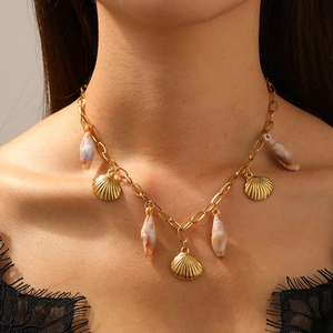 Collier en acier inoxydable doré avec pendentifs coquillages porté par un mannequin