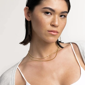 Elegant gold double-layered pearl necklace and tassel earrings worn by a fashion model