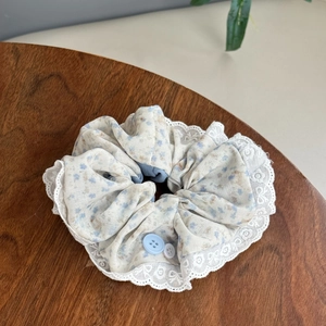 Detail of light blue floral scrunchie with white lace trim and decorative buttons
