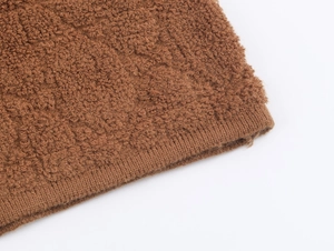Dettaglio macro del tessuto a maglia marrone con texture soffice e finitura del polsino
