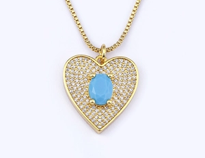 Close-up of gold-plated heart pendant with blue oval gemstone and pavé zircon accents