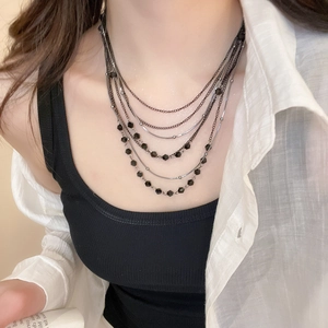 Detail of layered black crystal bead necklace on model with polished gunmetal chains