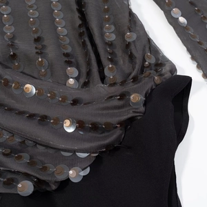 Detailed macro view of sequin embellishments on loose V-neck grey and black bodysuit