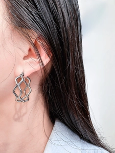 Macro detail of silver wavy textured double-layer hoop earrings worn by a model