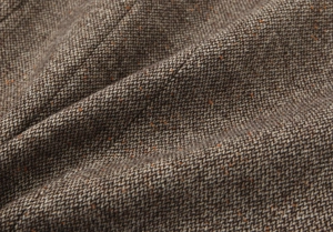 Dettaglio macro del tessuto tweed marrone con puntini arancioni e texture in lana