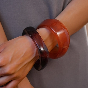 Close-up of retro amber-textured resin bangles with glossy irregular geometric design